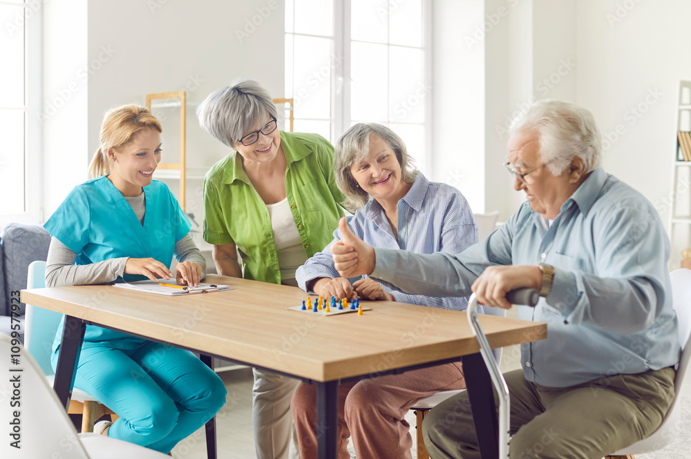 Obraz premium Happy elderly people playing a board game in a nursing home, close-up. Organization of leisure, events and entertainment for older people. Smiling nurse playing with old women and man