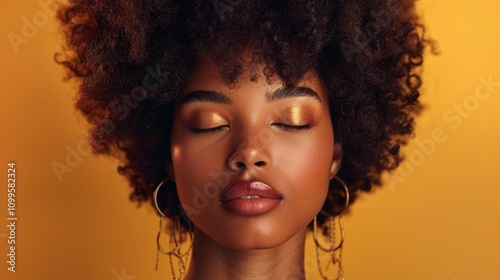 Model with beautiful afro hairstyle and golden makeup poses against a vibrant yellow background during a creative photoshoot