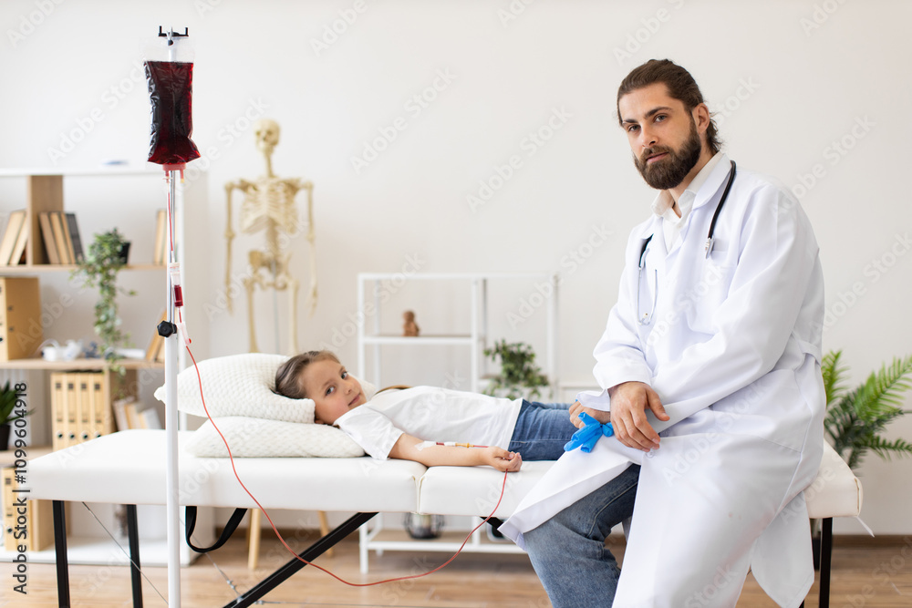 Obraz premium Young Caucasian girl receives blood transfusion from male doctor in a medical clinic. Doctor wears white coat, sitting beside girl on exam table. Blood bag hangs on IV stand.
