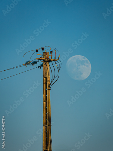 Moon rising against the backdrop of an electric pole photo