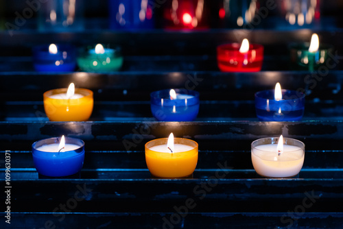 Illuminated atmosphere with colorful tealight candles on a shelf photo