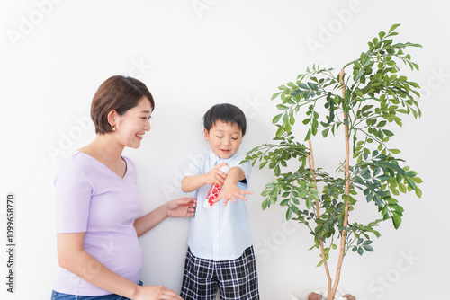 子どもにスプレーをするお母さん photo