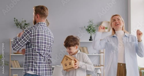 Happy new falt homeowners, family dancing celebrating moving day, child boy holding toy house, apartment keys, apartment purchase, buying real estate, move in new home, dwelling, loan, mortgage result photo