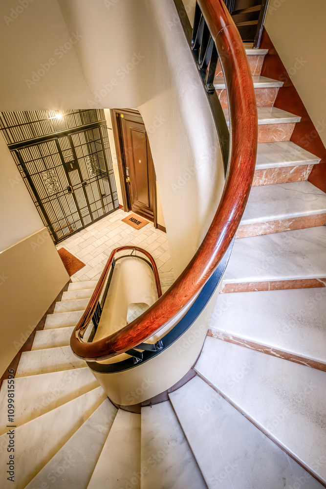 Spiral Staircase In A Residential Building In Barcelona, Spain The Staircase Features A Curved Wooden Handrail And Marble Steps, Leading To A Stylish Home Entrance