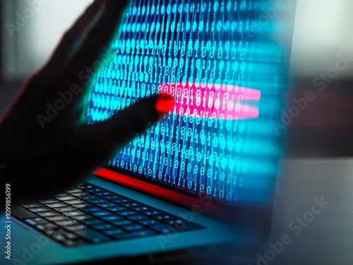 Hacker working over binary codes on laptop at desk photo