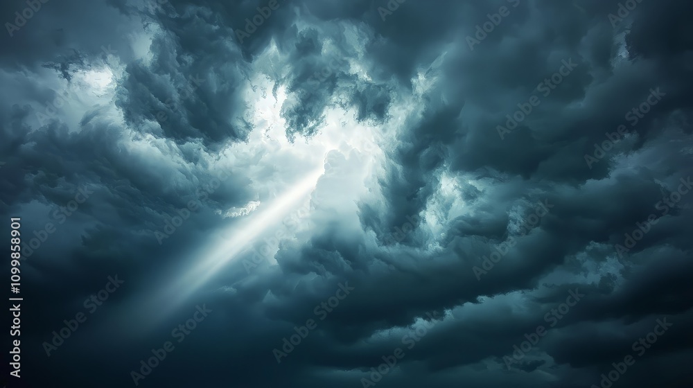 Obraz premium Dramatic light beam piercing dark stormy clouds.