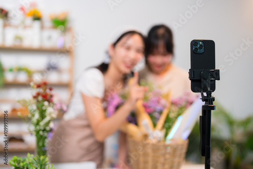 Two florists live-streaming flower sales, showcasing vibrant bouquets and engaging with an online audience in a cozy flower shop photo