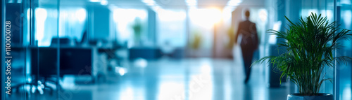 Wallpaper Mural A business professional walks through a modern office, with plants in the foreground and bright light filtering in from large windows. Torontodigital.ca