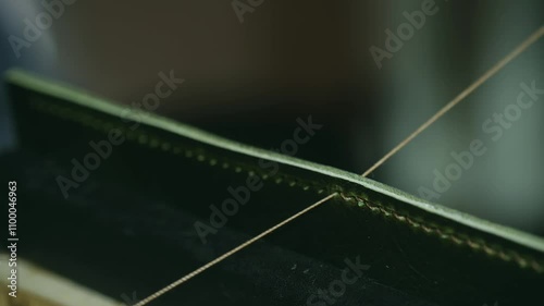 Craftsmanship shines as a skilled artisan stitches high-quality green leather with a needle and thread, showcasing precision and attention to detail in the traditional shoemaking process