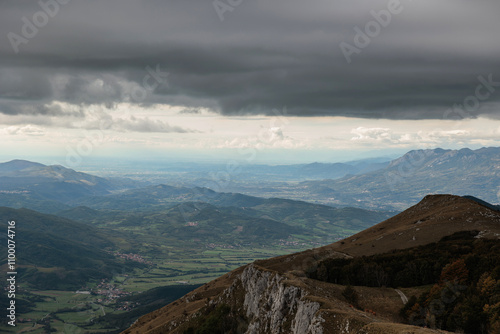 vista dettagliata dall'alto di una vasta zona ricca di catene montuose e collinari nella Slovenia occidentale, di pomeriggio, in autunno, sotto un cielo nuvoloso photo