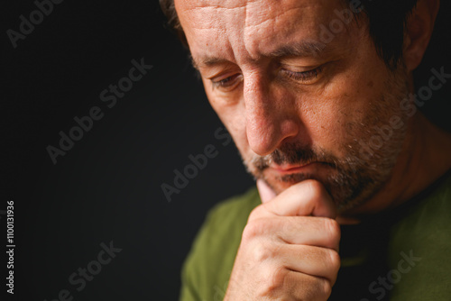 Portrait of tired mature adult man thinking in dark room photo