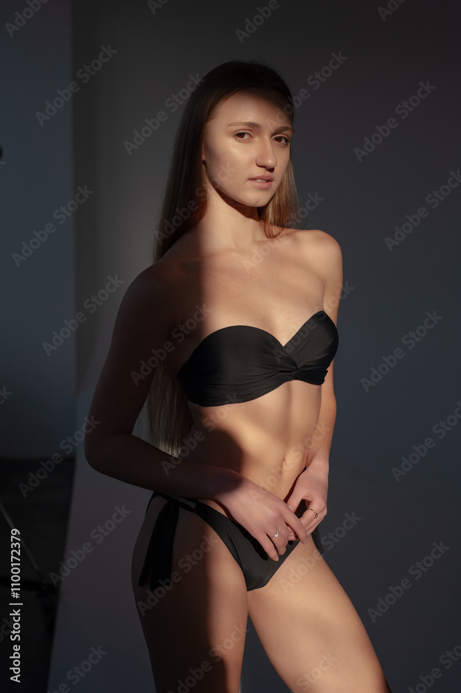 Fototapeta premium young woman in black lingerie and underwear posing on grey background. model agency test shoot