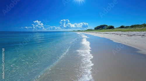 A pristine beach with crystal clear waters and a serene coastline under a bright blue sky on a sunny day, offering a tranquil and picturesque seascape
