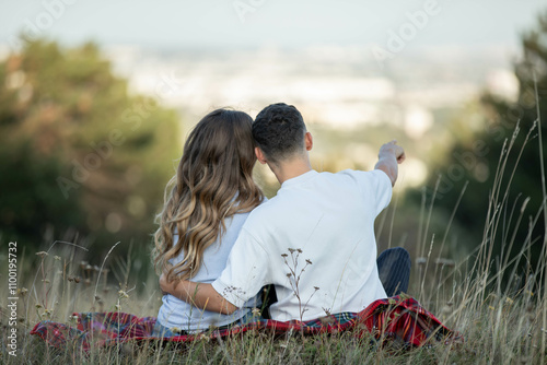 a young couple, boyfriend is pointing out something in the distance to his girlfriend