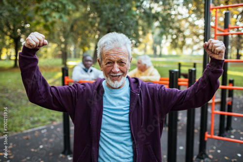 Portrait of a senior man exercising at outdoor fitness park in autumn photo