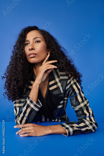 Striking portrait of a beautiful woman showcasing elegant fashion against a vibrant blue background