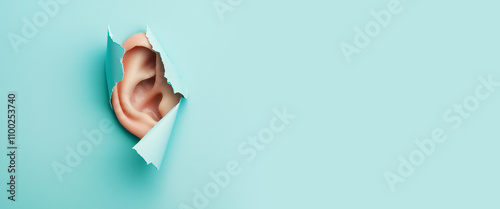 Ear peeking through a ripped blue paper, day of hearing loss, eavesdropping, espionage, gossip concept, attention and communication, torn hole photo