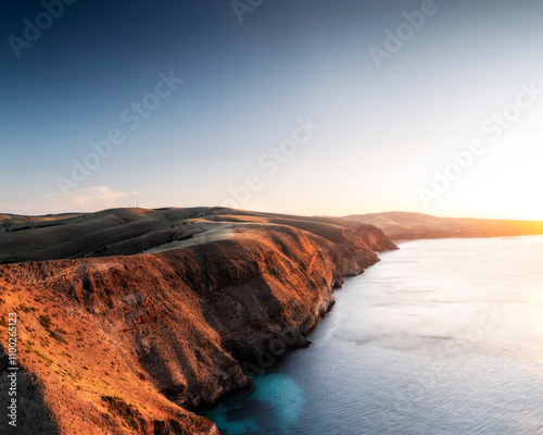 Aerial view of cliffs overlooking the ocean at sunset with a glowing horizon and clear sky, Second Valley, Australia. photo