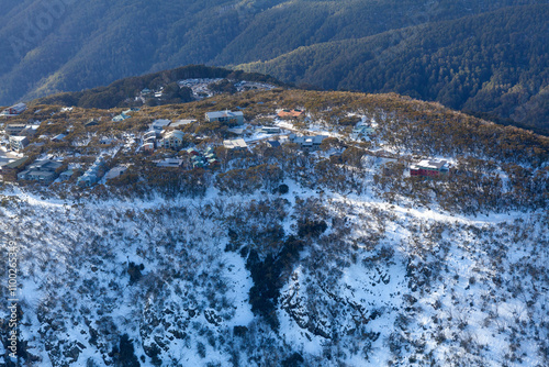 Aerial view of snowy Mount Buller ski resort surrounded by serene woodland and rugged mountains, Victoria, Australia. photo