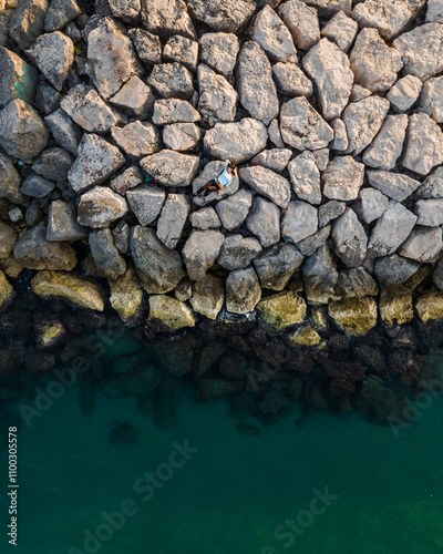 Aerial view of rocky coastline with a woman on the beach at sunset, Sitges, Spain. photo