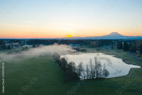 Aerial view of a tranquil lake surrounded by fog with a majestic Mt. Rainier in the background, Thurston County, United States. photo