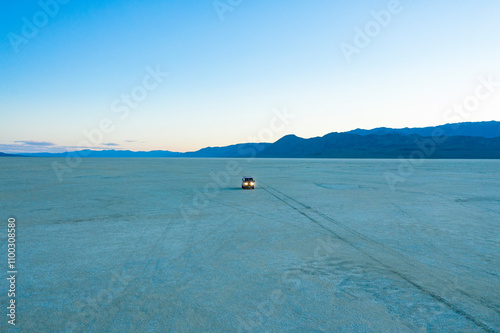Aerial view of a serene and expansive dry lake bed at dusk with a VW Vanagon in the Black Rock Desert, Black Rock City, United States.
