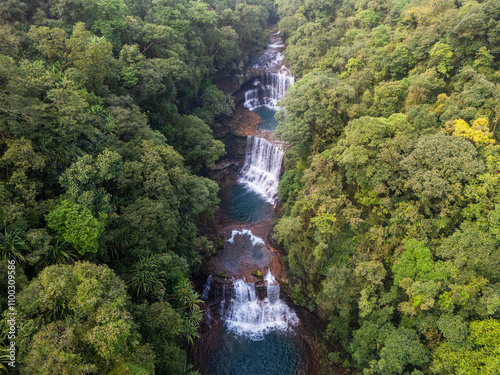 Aerial view of a breathtaking waterfall cascading through a lush green forest, Cherrapunji, India.