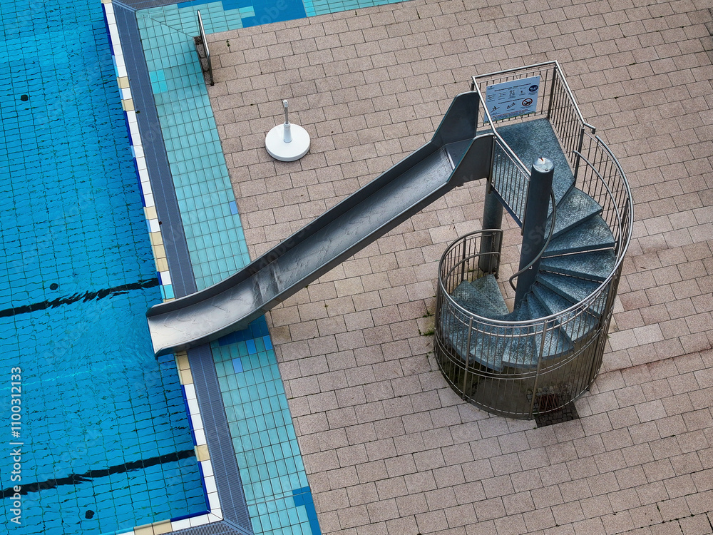 Aerial view of an empty public pool with a spiral staircase and slide ...