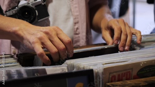 Closeup of mans hands choosing vinyl record, showcasing worn-out cover, Shelves in second hand shop with vinyl records, vintage technologies 80s, 70s disco.  photo