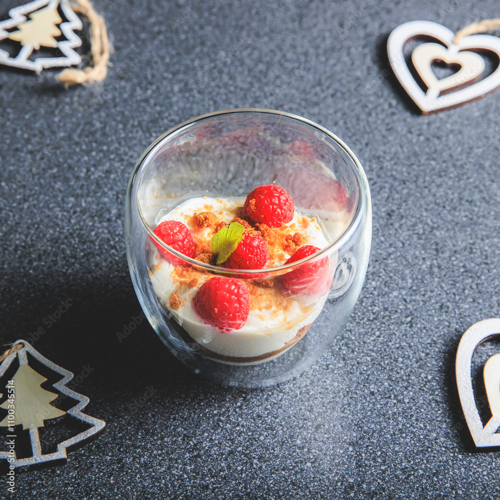 Verrine of crushed speculoos, mascarpone and raspberries on a gray background decorated for Christmas