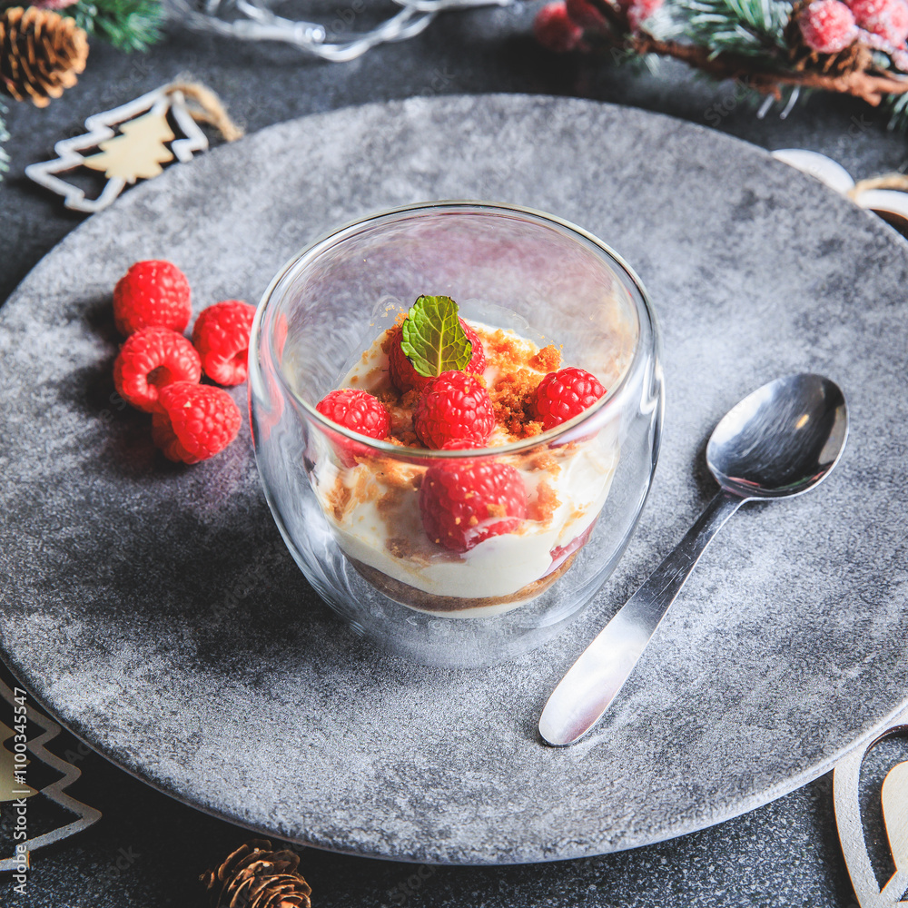 Verrine of crushed speculoos, mascarpone and raspberries on a gray background decorated for Christmas