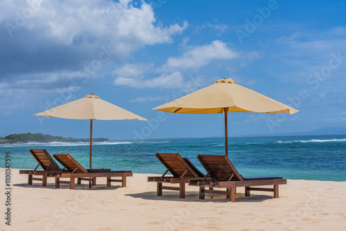 View of tranquil Nusa Dua beach with sun loungers and umbrellas under a clear blue sky, Bali island, Indonesia. photo