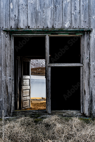 View of an abandoned shed with weathered wood and serene lake reflection, Sudavik, Iceland. photo