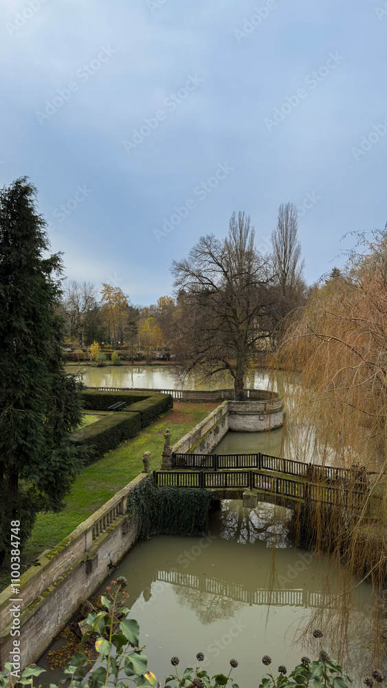 A pond with a bridge over it and trees in the background A pond with a bridge over it and trees in the background
