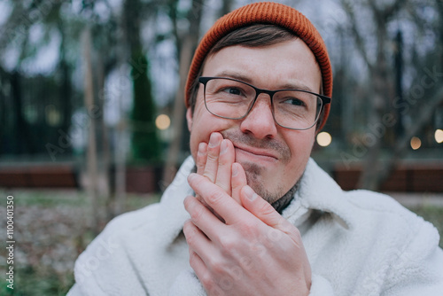 Worried man with a toothache in a park, feeling pain and stress, highlighting the importance of dental care in winter photo