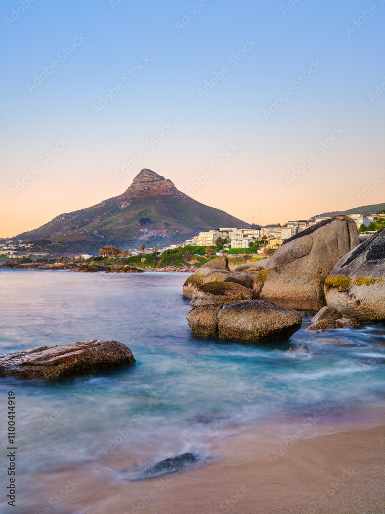 Sunset view of Lion's Head and Camps Bay behind the boulder at Beta Beach, vertical shot, Cape Town, South Africa