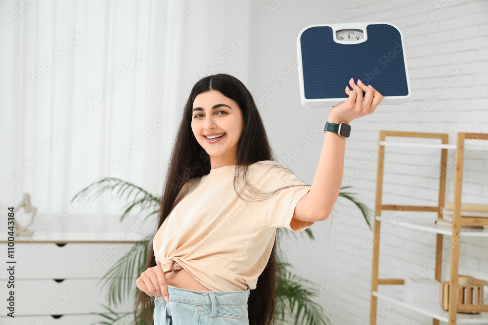 Φωτογραφία Beautiful young happy sporty woman in loose jeans with scales at home