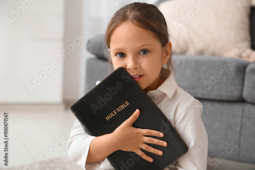 Cute little girl with Bible at home photo