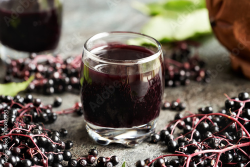 A cup of black elderberry syrup with fresh elder berries photo