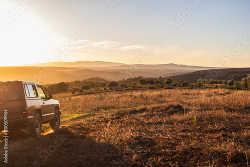 jipe a entrar no enquadramento, na montanha ao pôr-do-sol no horizonte