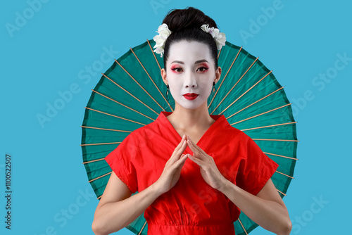 Beautiful young geisha with parasol on blue background photo