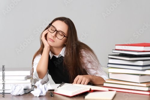 Young student having stress before exam at desk against grey background photo