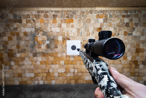 Shooting from a 22 LR rifle with a silencer and optical sight at a paper target in a shooting range. photo