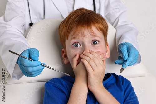 Dental phobia. Dentist working with scared little boy photo