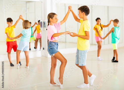 Portrait of happy modern tweenagers practicing active balroom dances in pairs in choreographic studio. photo