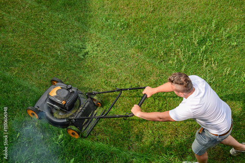 Top down view of a man mowing green grass lawn