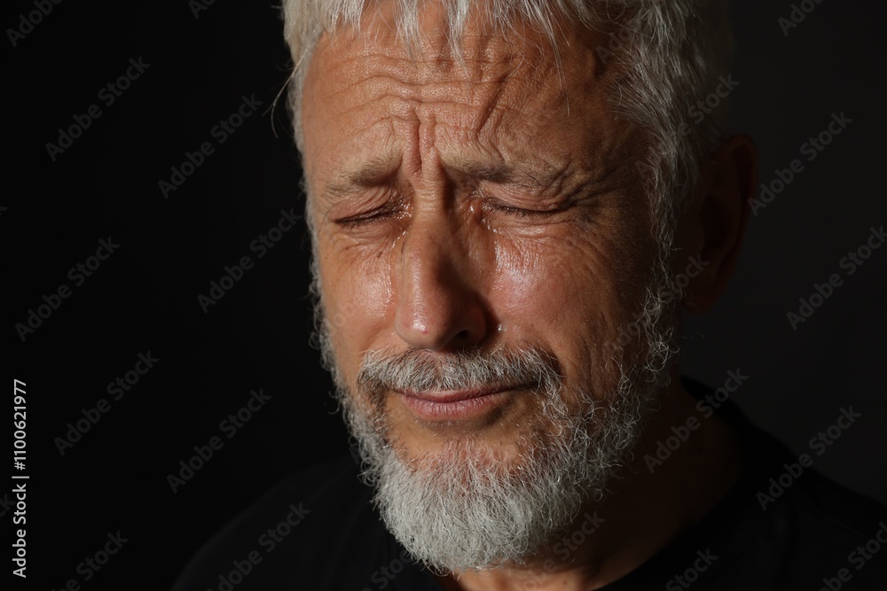 Fototapeta premium Sad senior man crying on black background, closeup