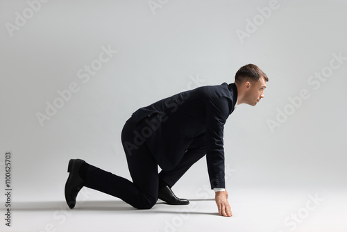 Businessman in starting position for run on light grey background photo