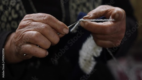 Old woman's hands knitting with crochet hook. Grandma crocheting with white knitting. Handicraft concept