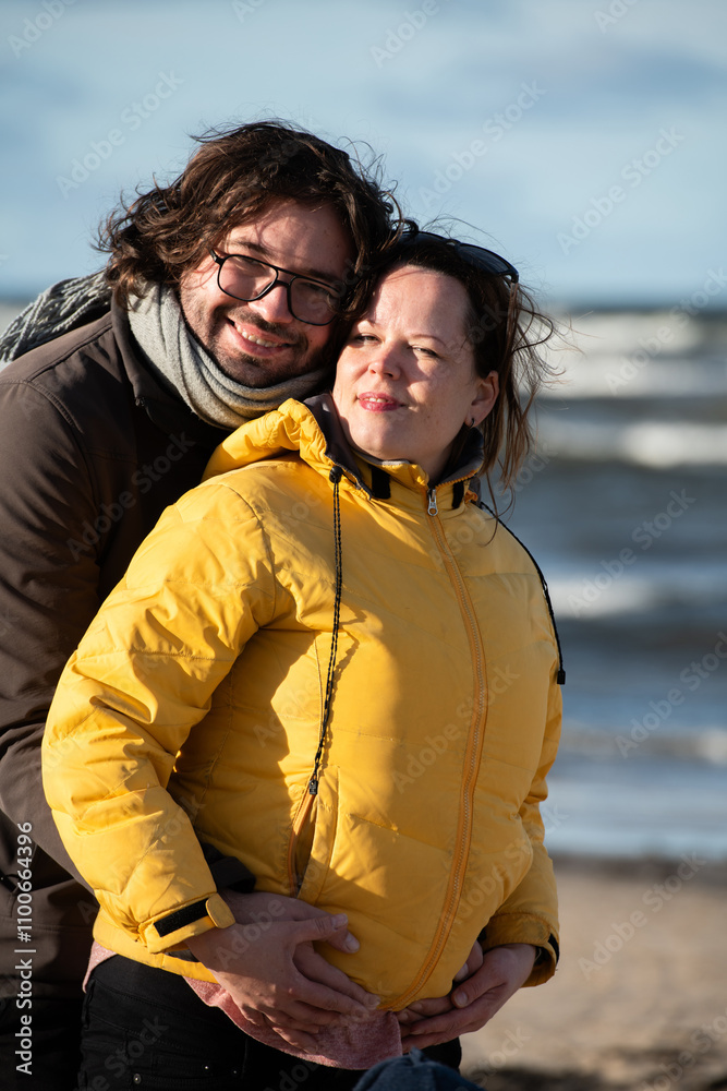 A couple stands embraced on a sandy beach on a chilly autumn day, the serene ocean stretching behind them as they share a quiet moment of love and warmth amidst the cool breeze and peaceful A couple stands embraced on a sandy beach on a chilly autumn day, the serene ocean stretching behind them as they share a quiet moment of love and warmth amidst the cool breeze and peaceful